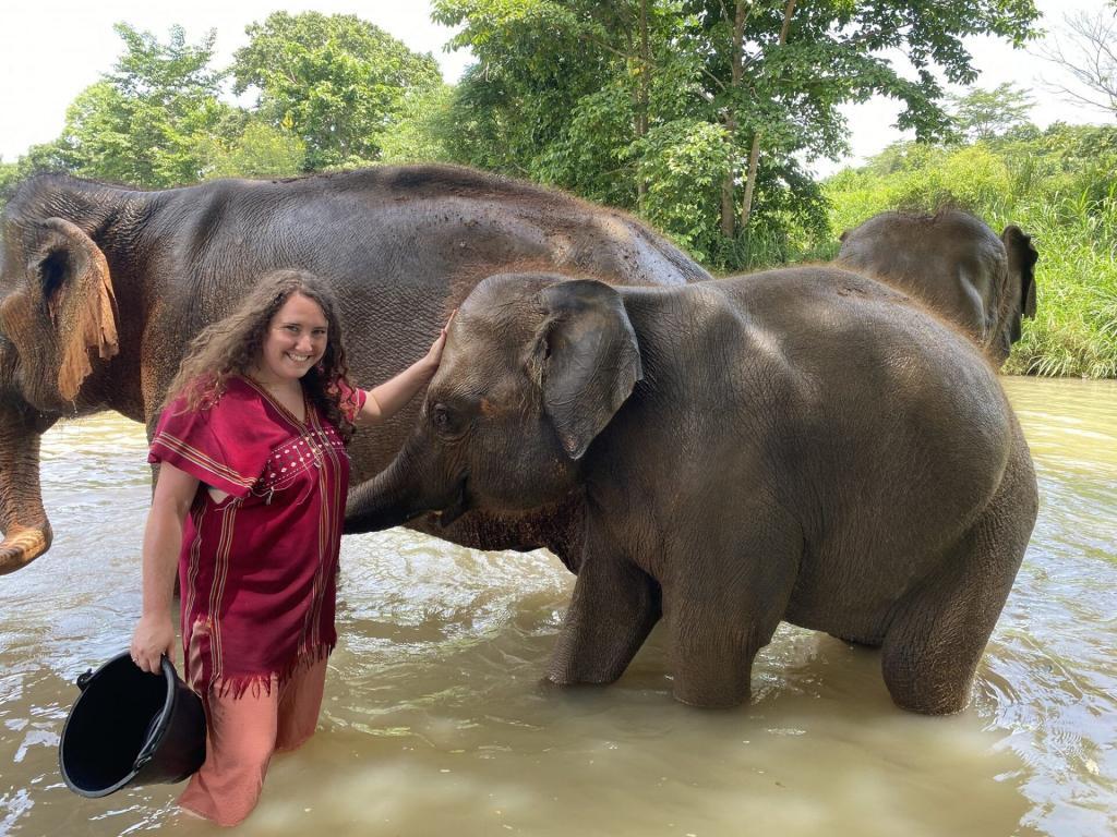 A woman standing in water with an elephant at the Elephant Freedom Project.