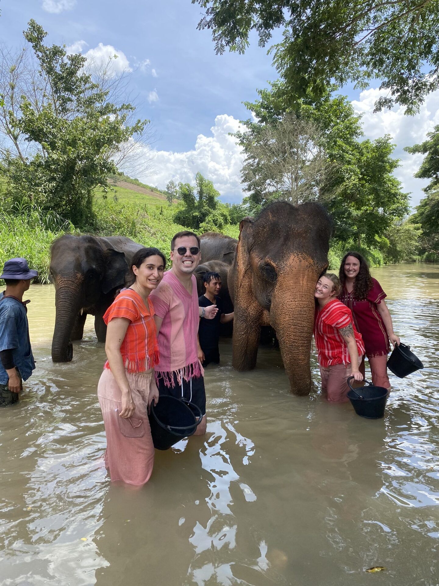 A group of people standing in water with elephants at the Elephant Freedom Project.