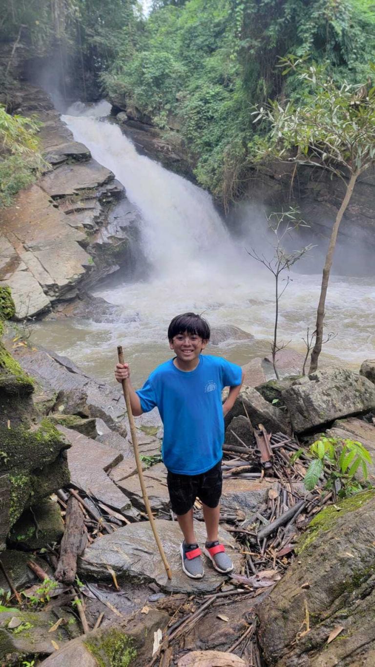 A boy standing on rocks with a stick in front of a waterfall is featured in the Image Gallery.