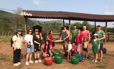 A group of people posing for a picture in front of an Elephant Sanctuary in Chiang Mai.