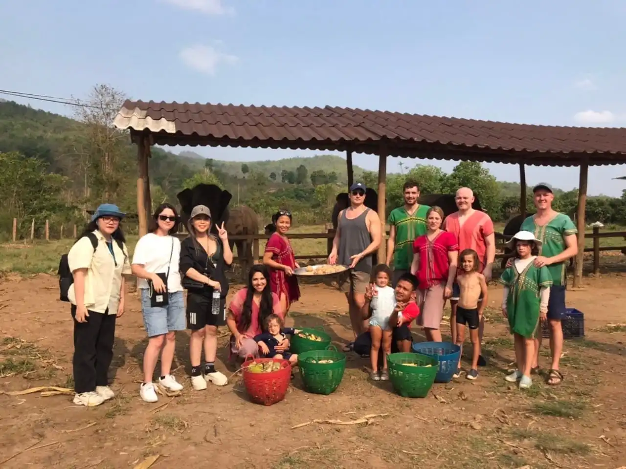 A group of people posing for a picture in front of an Elephant Sanctuary in Chiang Mai.