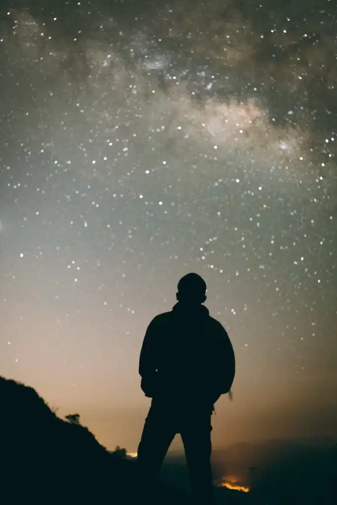 A man is standing on top of Doi Inthanon looking at the stars.